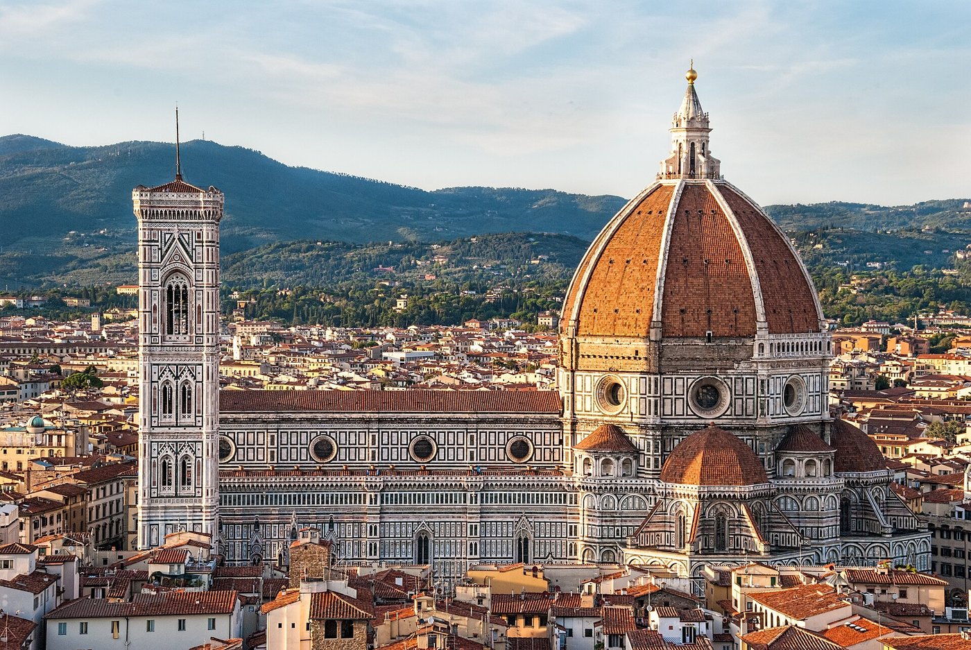 View of the Florence skyline at golden hour, with the Duomo's dome and bell tower rising over the terracotta rooftops.